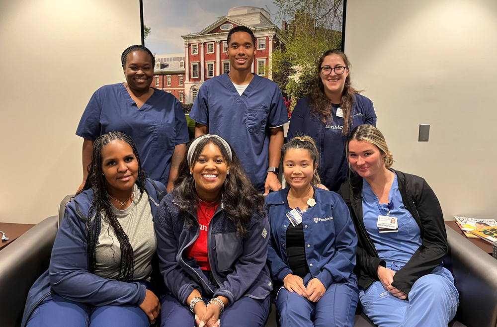 The Delancey Internal Medicine Nurse Triage Team poses for an indoor photo. Four members of the team are sitting on a couch and the three remaining members of the team standing behind them. 